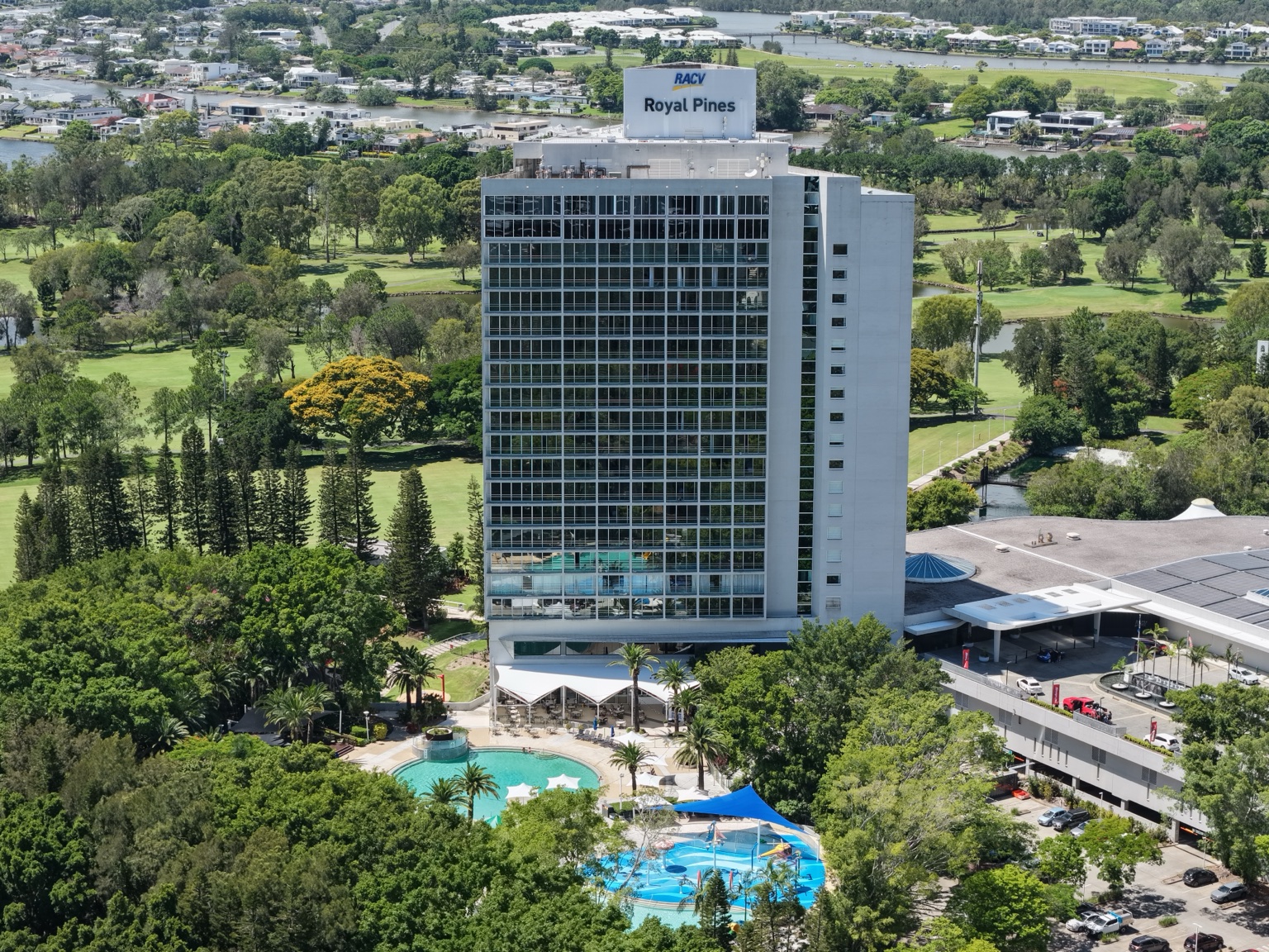 Front aerial view of RACV Royal Pines Resort with the tower glazing, pool and resort grounds visible.