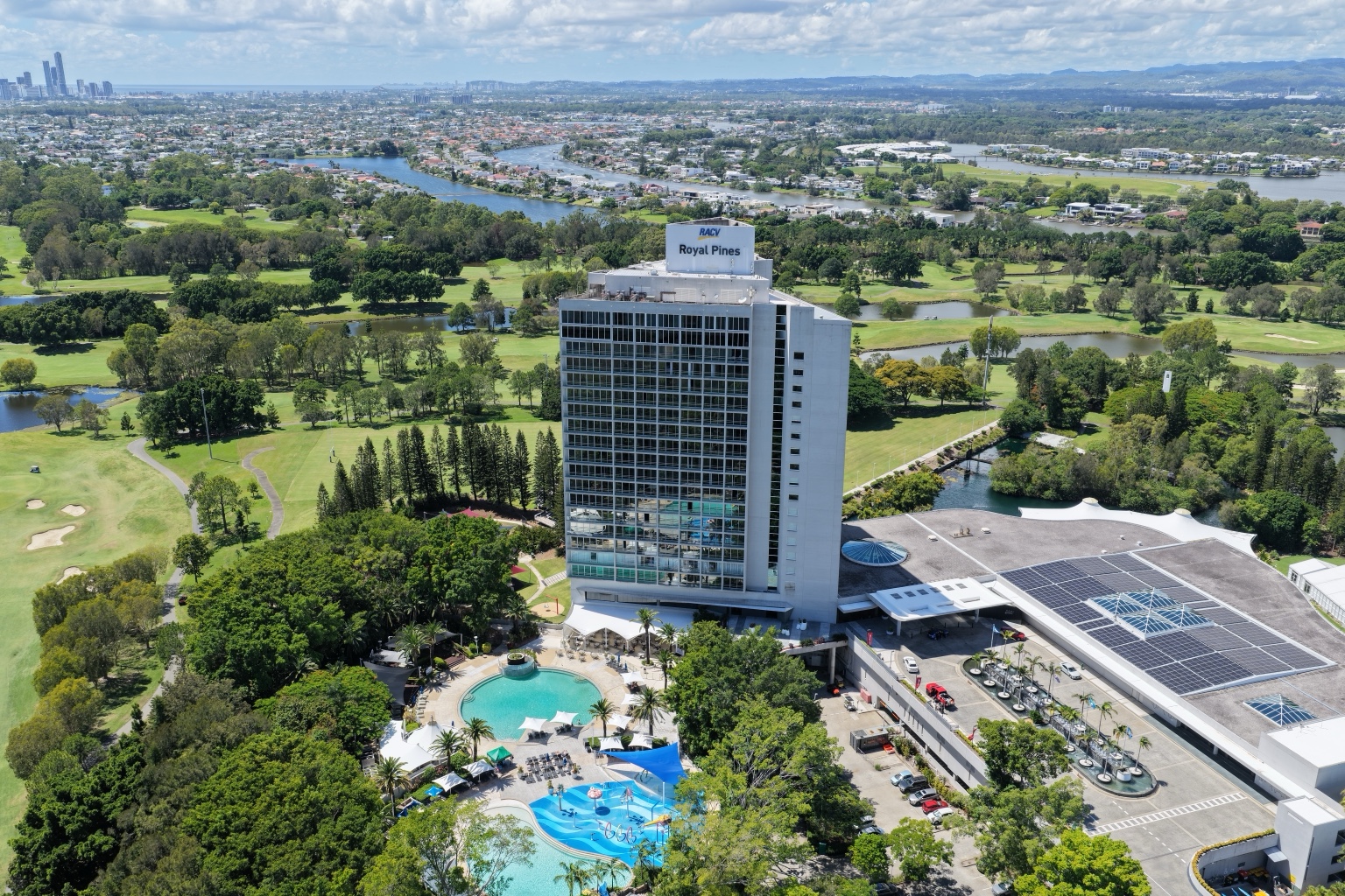 Drone view of RACV Royal Pines Resort with the Gold Coast skyline and waterways in the distance.